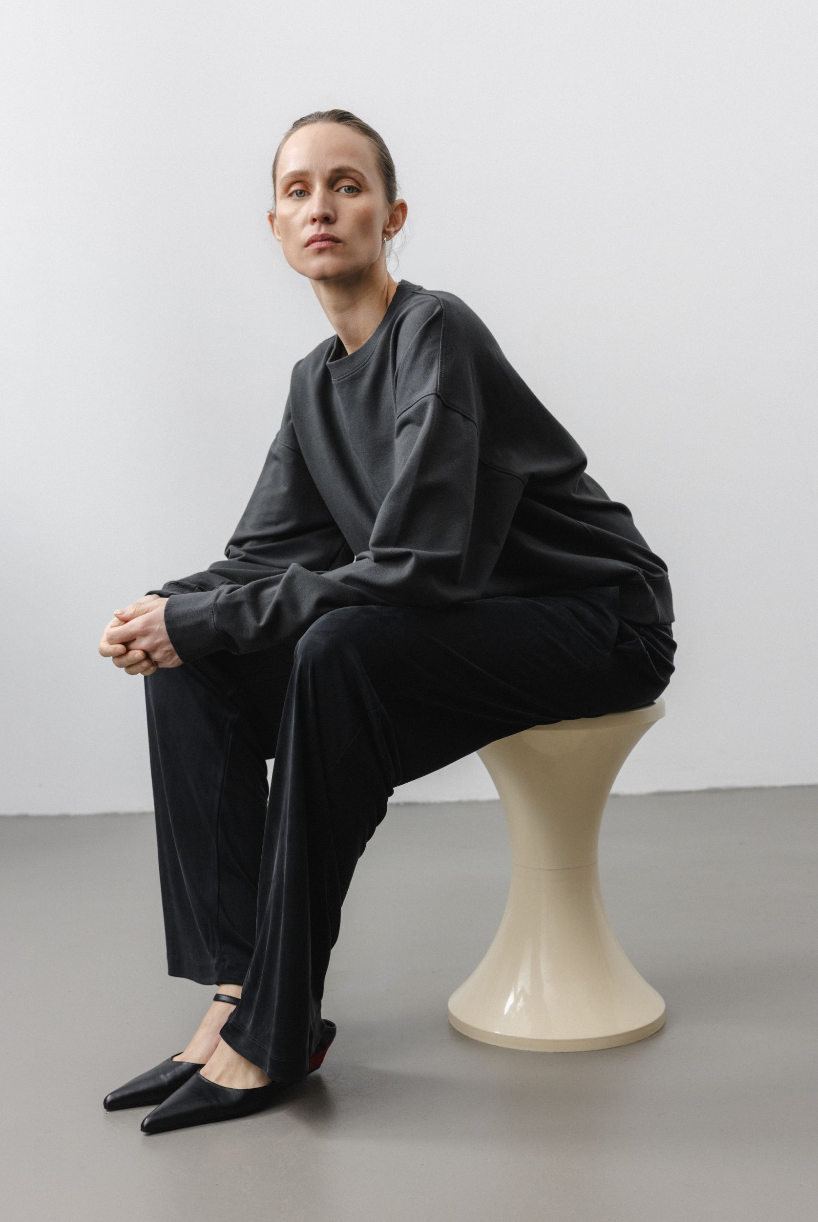 The May in Pitch Black. Crew-neck sweater with a boxy shape. 100% organic cotton babyfleece. GOTS. Shown on model with The Sam in Essential Black.