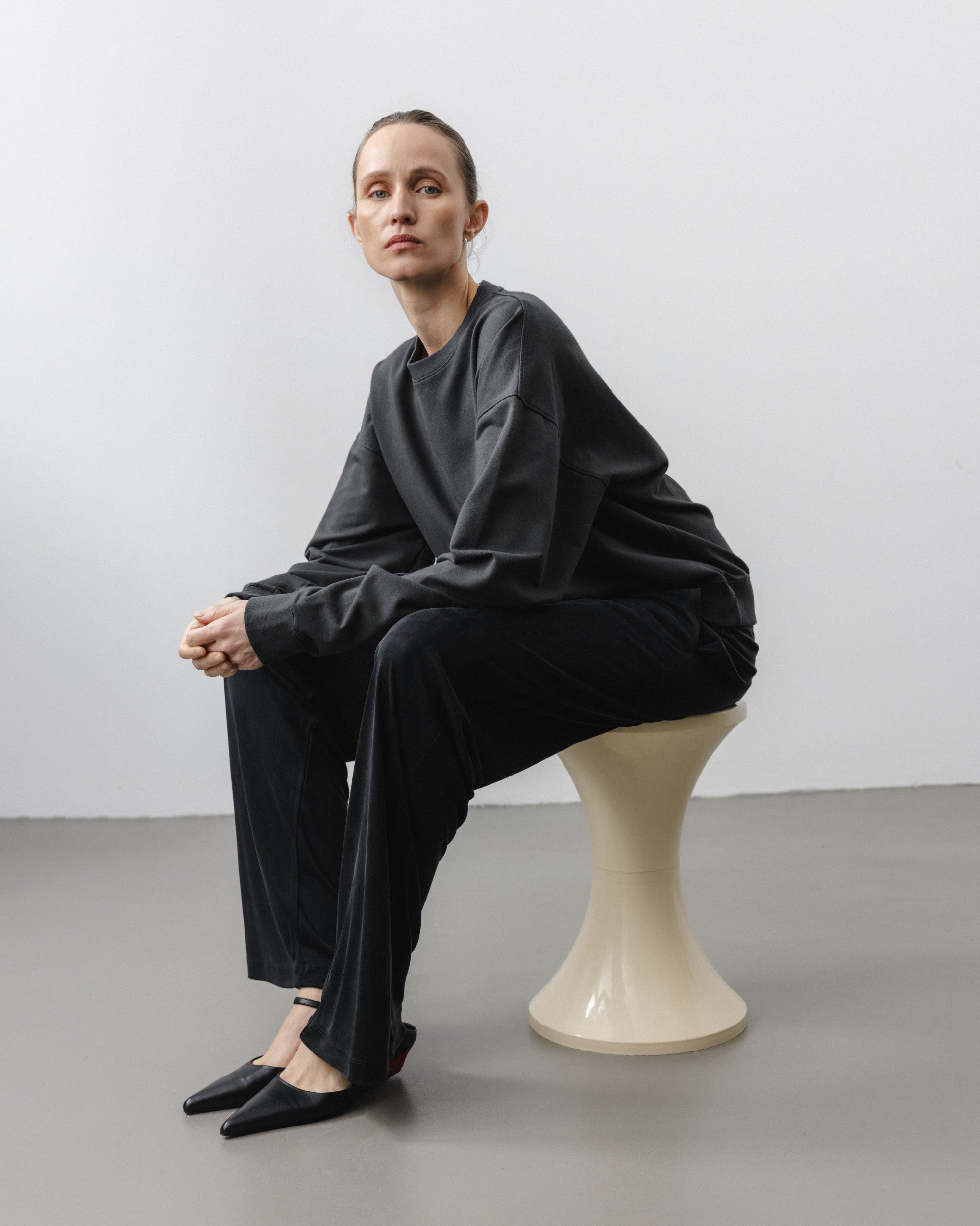 The May in Pitch Black. Crew-neck sweater with a boxy shape. 100% organic cotton babyfleece. GOTS. Shown on model with The Sam in Essential Black. 