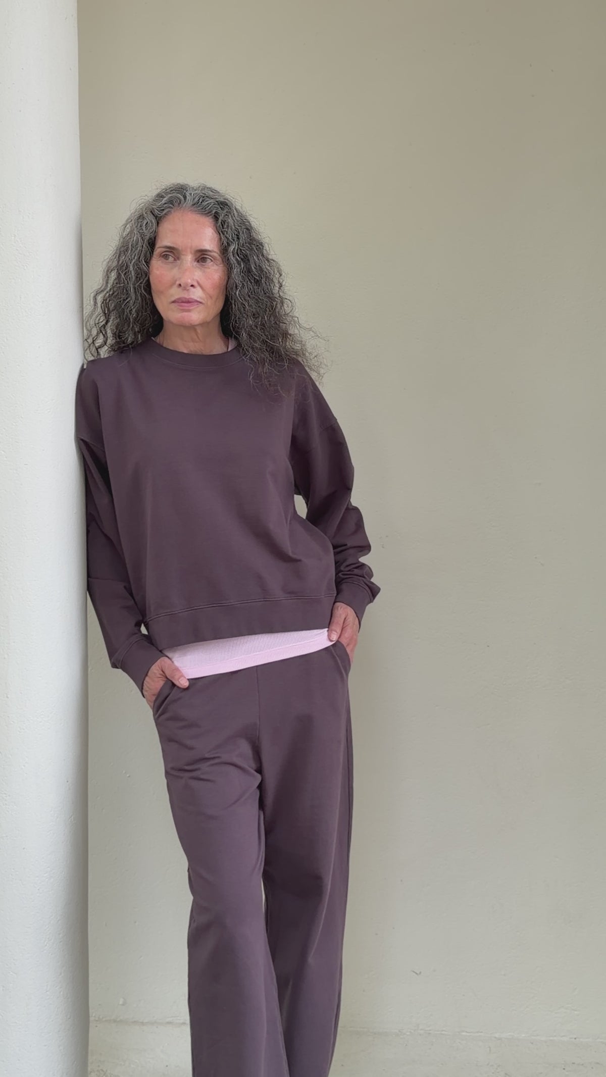 The May in Plum. Crew-neck sweater with a boxy shape. 100% organic cotton babyfleece. Shown on model together with The Erin top in Rose Pink and The Riley sweatpants in Plum.
