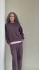 The May in Plum. Crew-neck sweater with a boxy shape. 100% organic cotton babyfleece. Shown on model together with The Erin top in Rose Pink and The Riley sweatpants in Plum.